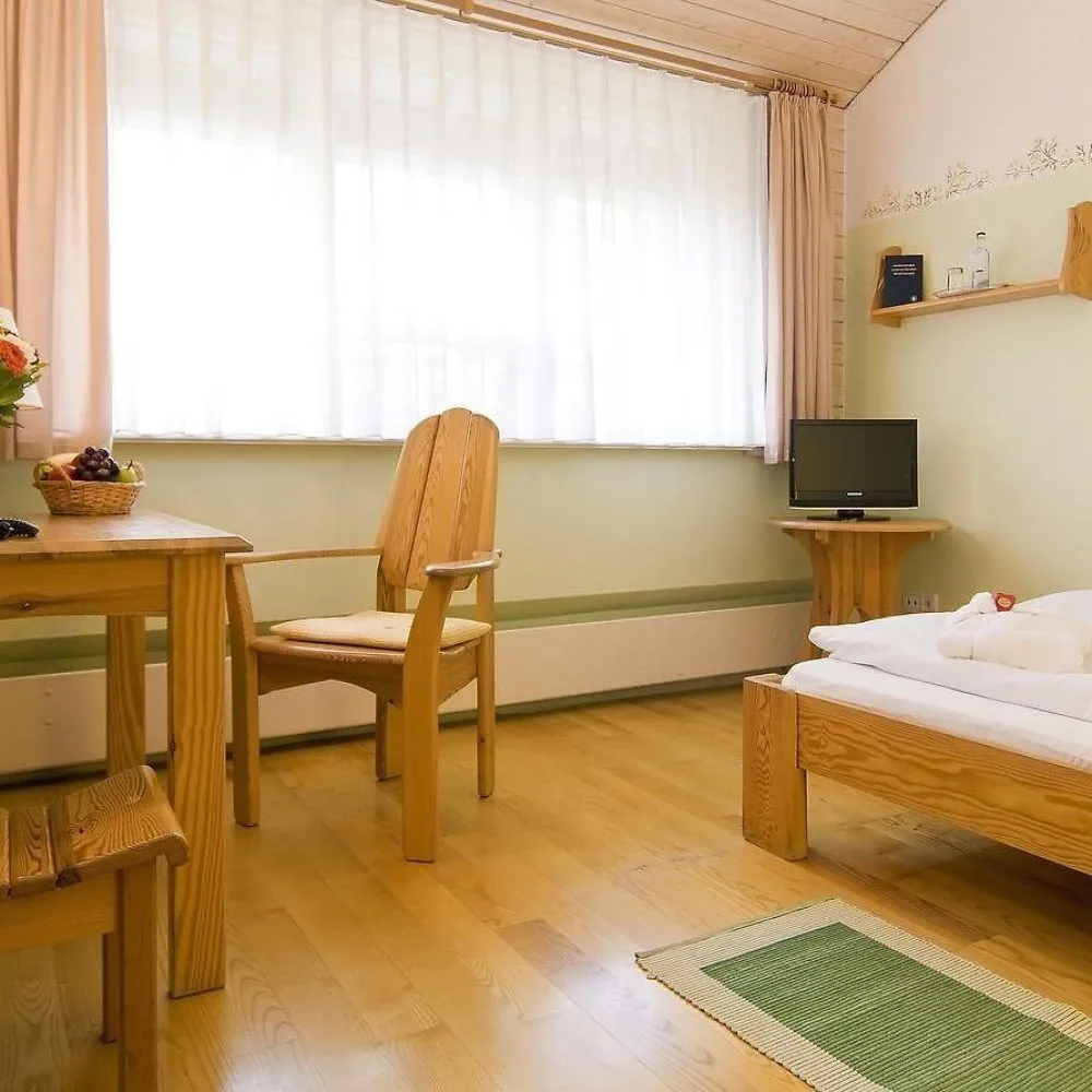 Helles Doppelzimmer mit Fensterfront, Sessel und Fernseher