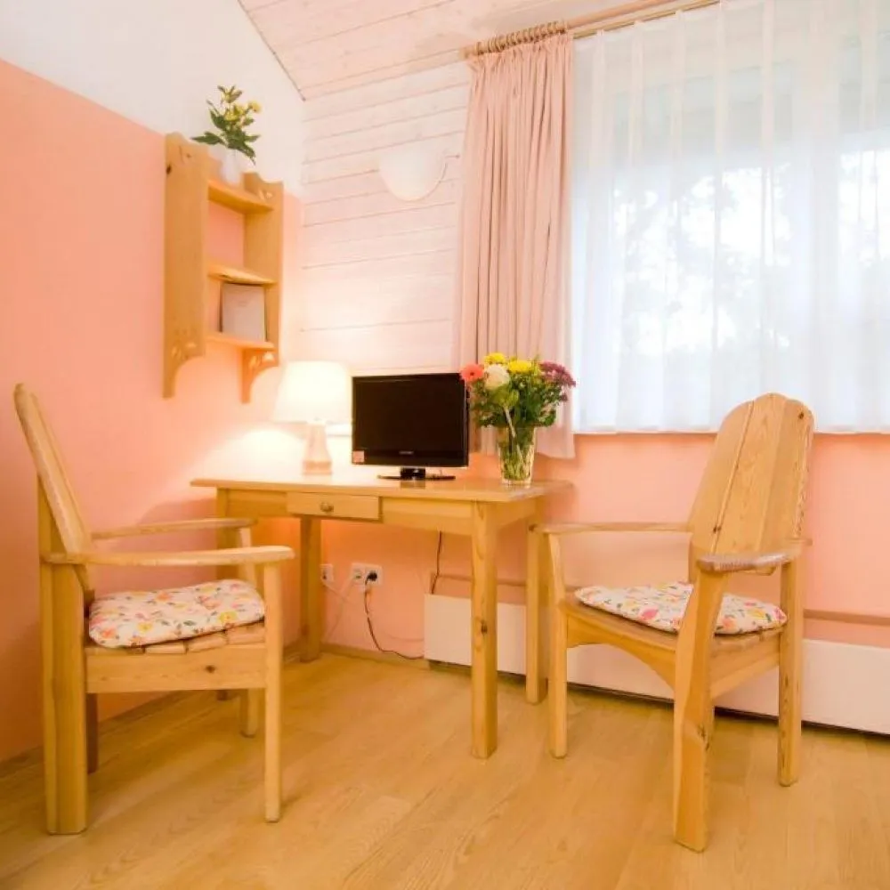 Schreibtisch mit Fernseher und zwei Holzsesseln im Doppelzimmer