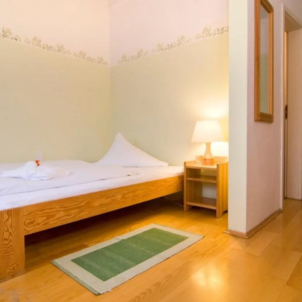 Einzelzimmer mit Einzelbett, Nachttisch und Lampe